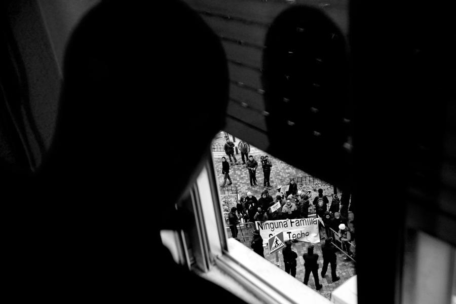 Uno de los compañeros de piso de Antonio Tomás observa por la ventana el despliegue policial y la concentración de protesta por su desahucio momentos antes de ser desahuciado. Leganés 14 de diciembre de 2011. Foto: Olmo Calvo