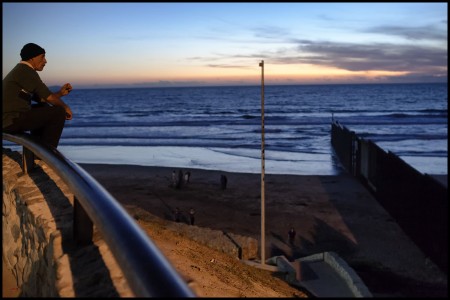 Un hombre mira hacia los Estados Unidos desde el muro de Tijuana